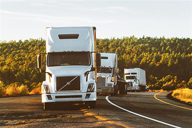 Three white trucks driving
